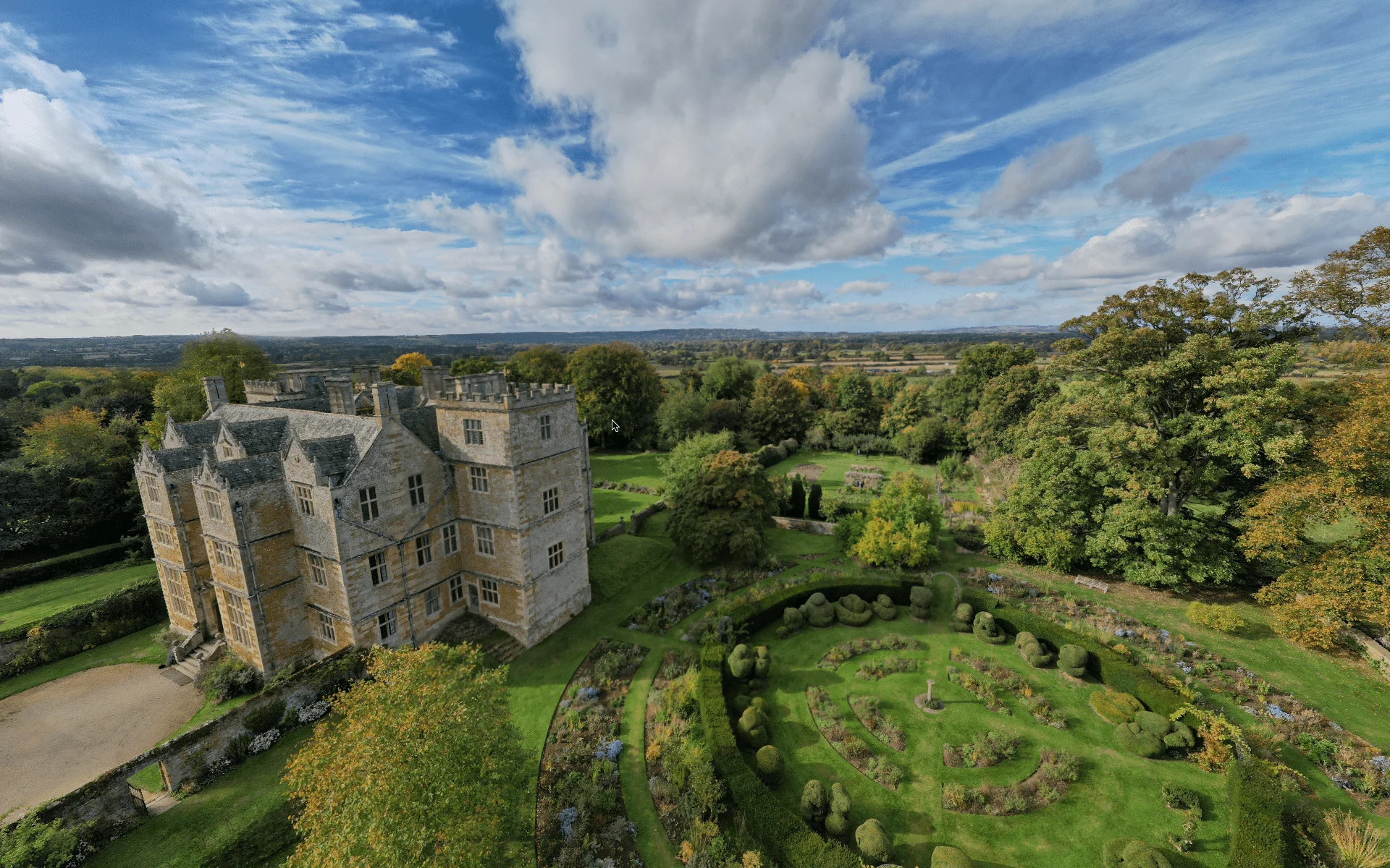 Aerial view of a historic house, formal gardens and surrounding countryside